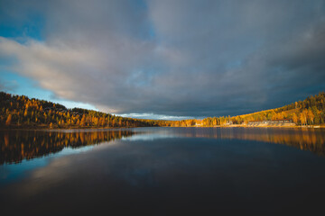 Autumn sunset at Lake Syvajarvi, in Hyrynsalmi, Finland. Reflection of red-orange petals on the lake surface. Storm clouds at sunset. Autumn vibes