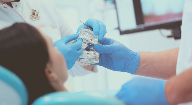 Senior male dentist in dental office talking with female patient and preparing for treatment