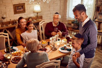 Happy Jewish extended family enjoys in lunch at dining table on Hanukkah.