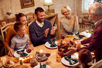 Happy multi-generation family has traditional Christmas turkey for lunch at dining table.