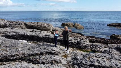 Aerial photo of Woman and child standing Rocks Mountains and Sea on Beautiful Scenery the North Coast of Ireland