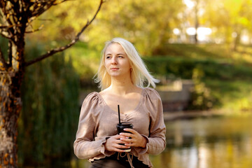 Young blonde woman in the park on a background of yellow autumn foliage