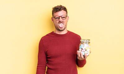 young handsome man feeling disgusted and irritated and tongue out. jelly candies concept