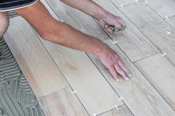 The hands of the tiler lying or installing modern, ceramic tile above cement on the garden terrace , tiling floor, building concept