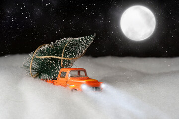 car carrying a Christmas tree. night sky with a big moon in the background.