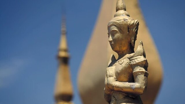 Wat Xieng Thong, Luang Prabang. Laos.  Close up of buddhist deity praying in namaste mudra.