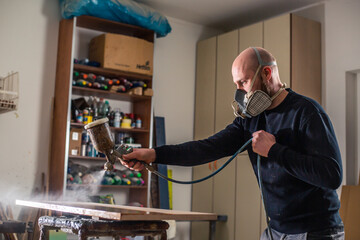 Joinery, woodworking and furniture making, professional carpenter varnishing a wood in carpentry...