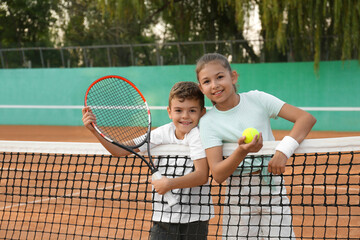 Happy children with tennis racket and ball on court outdoors