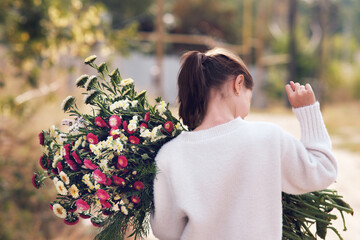 The girl holds in her hands a large bouquet of flowers and folded her Fig gesturing fig sign in a gesture of refusal