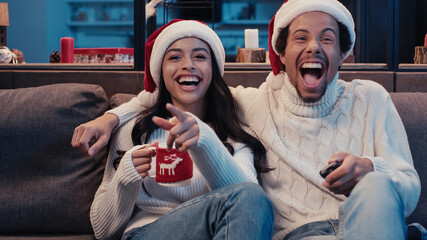 cheerful african american couple watching comedy movie on christmas