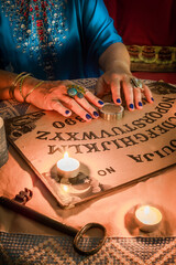 The hands of a Pythoness on a Ouija board to initiate a seance on Halloween