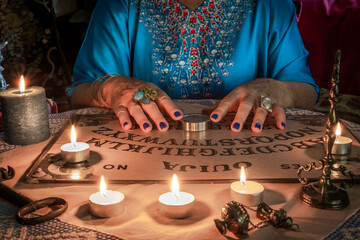Ouija board with the hands of a fortune teller on the table