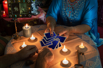 The Pythoness chooses a Tarot card in an esoteric session with candles