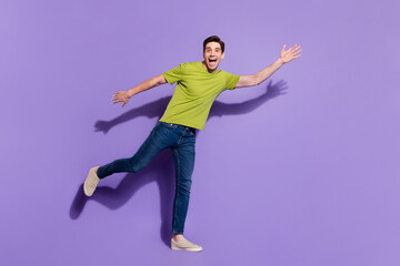Photo of funky impressed young guy dressed green t-shirt smiling dancing waving arm isolated purple color background
