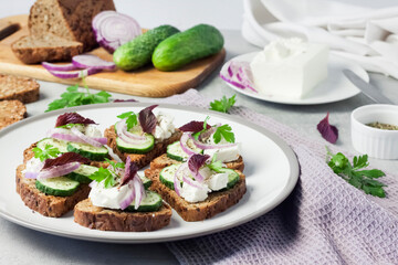 Canapes with toasted bread with sunflower and flax seeds, feta cheese, cucumber and onion