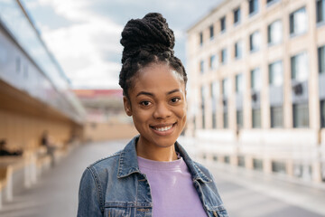 Close up portrait of smiling African American student standing in university campus. Education...