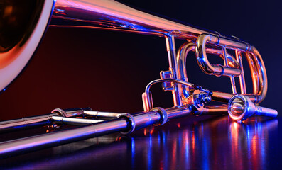 Jazz trombone illuminated with colored lights on black table - obrazy, fototapety, plakaty