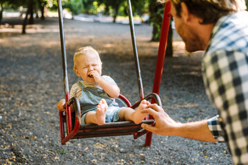 White father swinging his son on swing at playground