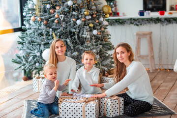 Happy kids near the Christmas tree with the present boxes