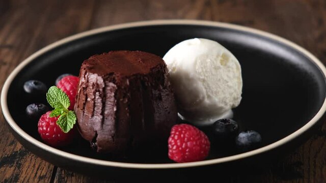 Chocolate fondant cake and ice cream scoop. Sweet dessert food on black plate