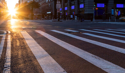 Empty intersection on 14th Street and 5th Avenue with light of sunset shining between the...