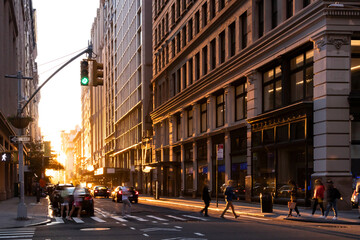 Busy intersection with crowds of people walking through an intersection on 5th Avenue in New York City with summer sunlight shining