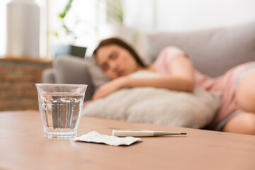Fototapeta na wymiar Young woman is sick, unwell, cold and sleep on the sofa. After taking medicine