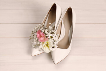 Women's shoes with beautiful flowers on beige wooden background