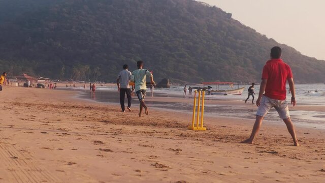 Men play cricket on beach