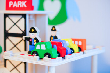 Selective shot of a row of wooden toy cars on a toy garage with policemen in the kindergarten