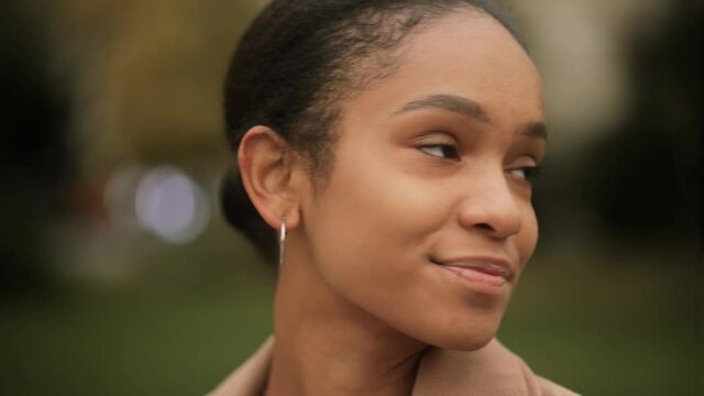 Portrait of attractive Afro American girl. Young beautiful girl at the street. Happy smiling girl looking at the camera. High quality 4k footage