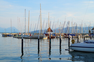 Obraz premium a beautiful marina of Lindau island on lake Constance (Bodensee) with the sunlit Alps in the background, Germany