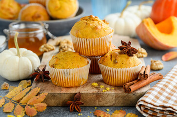 Pumpkin muffins or cupcakes with walnuts on a wooden board. Autumn spicy bakery. Healthy vegetarian dessert. Selective focus 
