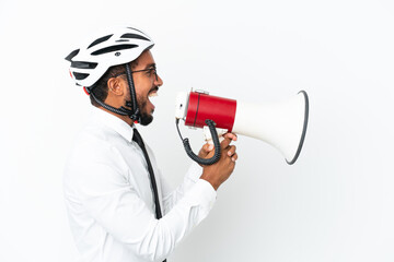 Young business latin man holding a bike helmet isolated on white background shouting through a megaphone