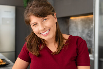 happy woman looking at camera and smiling in the kitchen