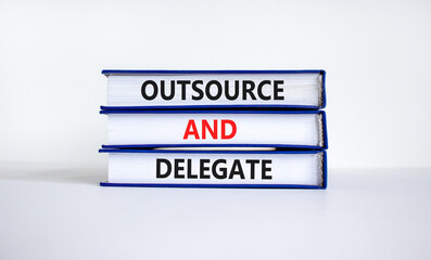 Outsource and delegate symbol. Concept words 'Outsource and delegate' on books. Beautiful white...