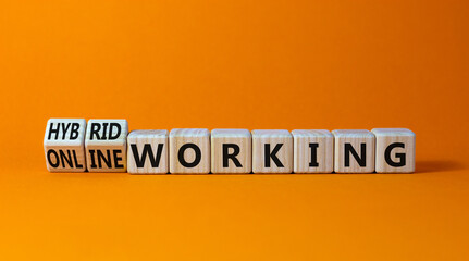Hybrid or online working symbol. Turned wooden cubes and changed words 'online working' to 'hybrid working'. Beautiful orange background. Business, hybrid or online working concept, copy space.