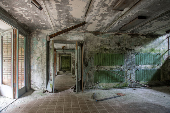 A scary room with a staircase in an abandoned building. Dirty and shabby walls. Stairs with steps. An empty forgotten place. Corridor with a window.