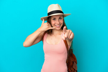 Young caucasian woman in summer holidays isolated on blue background making phone gesture and pointing front