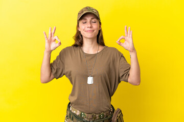 Military caucasian woman with dog tag isolated on yellow background in zen pose