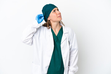 Surgeon caucasian woman in green uniform isolated on white background having doubts and with confuse face expression