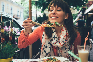 Smiling young female happy to eat italian vegetarian pizza and coffee latte for lunch at outdoor italian restaurant