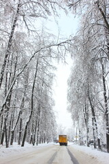 Winter snow-covered landscape with a road and a yellow car. A picturesque and magnificent winter scene. Great winter wallpaper. Christmas, New Year background.