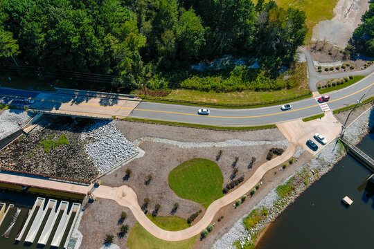 A Stunning Aerial Shot Of The Lake Surrounded By Lush Green Trees And The Street Along The Lake With Cars  At Lake Peachtree In Peachtree City Georgia