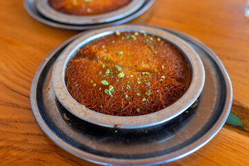 Turkish dessert kunefe, kunafa, kadayif with pistachio powder and cheese, served hot, very sweet.