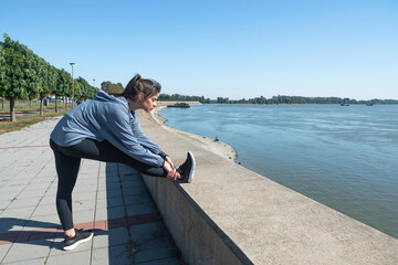 Young beautiful happy sporty fitness woman standing outdoor stretching her muscles preparing for jogging and running exercise while preparing for workout and training motivation for marathon