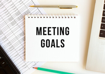 Notepad with text MEETING GOALS on a white background, near laptop, calculator.