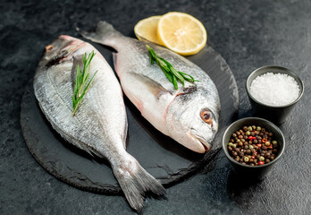 raw dorado fish with lemon and rosemary on stone background