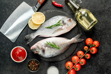 raw dorado fish with lemon and rosemary on stone background