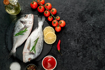 Obraz na płótnie Canvas raw dorado fish with lemon and rosemary on stone background with copy space for your text
